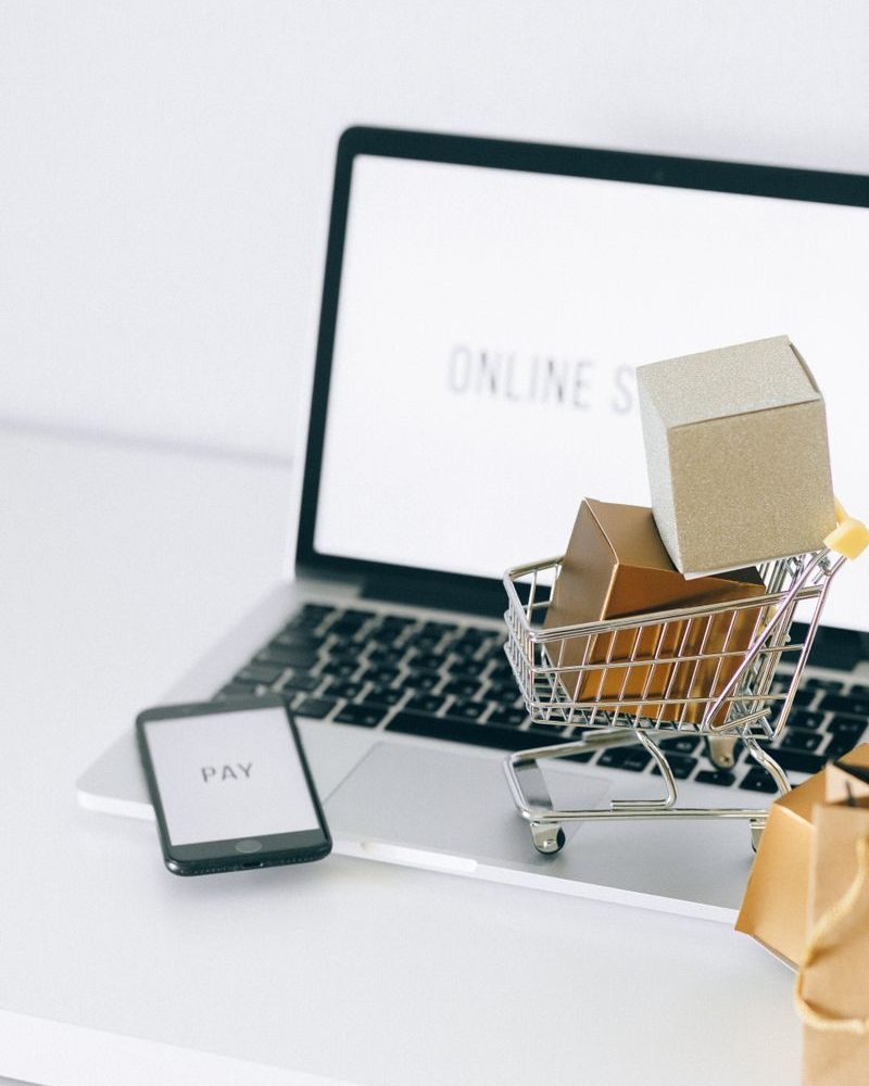Mini shopping cart on laptop symbolizing online shopping and e-commerce transactions.